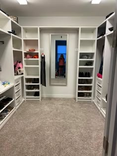 a walk in closet with white shelving and drawers