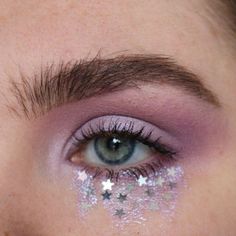 a close up of a person's eye with stars painted on the bottom of their lashes