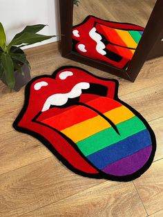 the rug is shaped like a rainbow tongue with white teeth on it and has a mirror behind it