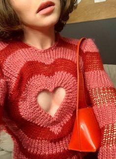 a woman in a pink sweater holding a red purse