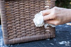 a person is cleaning a wicker basket with a cloth wipes the edges off