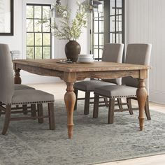 a dining room table with chairs and a vase