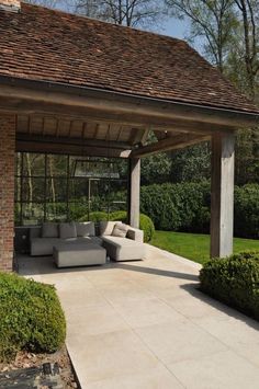 an outdoor living area with couches and bushes