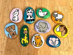 rocks with different animals painted on them sitting on a wooden floor next to each other