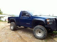 a blue pick up truck parked on top of a dirt road