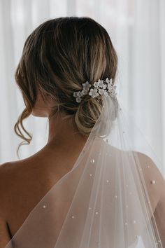 a woman wearing a veil with flowers on it's head and hair comb in her hair