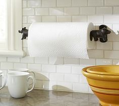 two cups and a toilet paper roll on a counter in a bathroom with white tiles