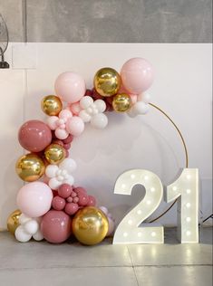 a number twenty sign with balloons in the shape of a wreath on top of it