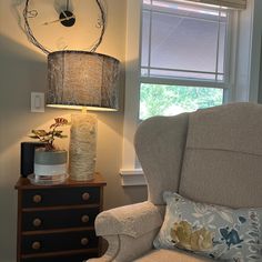 a living room with a chair, lamp and clock hanging on the wall above it