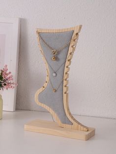 a wooden stand with a necklace holder on it and a flower vase in the background