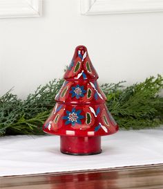 a red ceramic christmas tree sitting on top of a wooden table