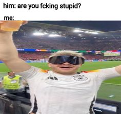 a man in a white shirt and goggles holding up two beer mugs at a soccer game