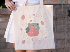 a person holding a white bag with strawberries on it and an image of a frog