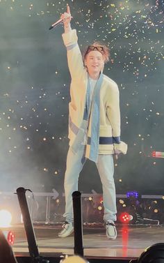 a man standing on top of a stage with his arms in the air and confetti falling around him