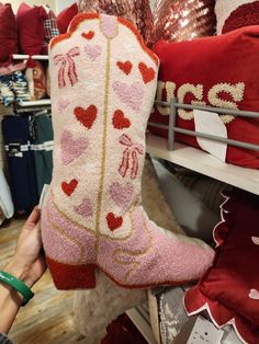 someone is holding up a pair of pink cowboy boots with hearts on them in a store