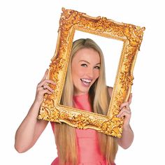 a woman in a pink dress holding up a gold frame with an image of herself