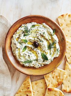 a bowl filled with hummus and olives next to crackers