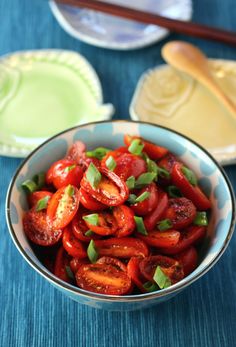 a bowl filled with sliced tomatoes on top of a blue table