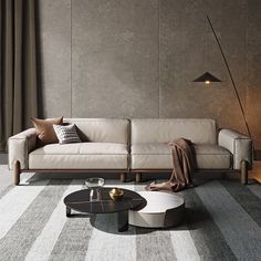 a living room with a couch, coffee table and lamp on the floor in front of a gray wall