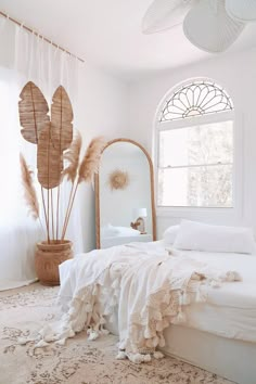 a bedroom with a bed, mirror and large plant in it's centerpiece