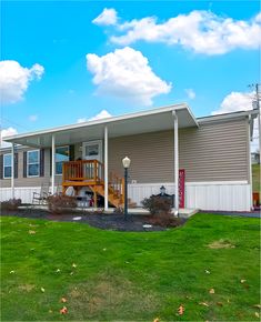 a mobile home sits in the grass with a porch and stairs leading up to it