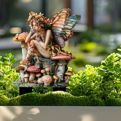 a statue of a fairy sitting on top of mushrooms