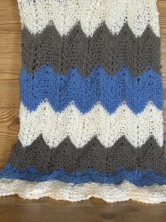 a crocheted blanket on top of a wooden floor next to a wood wall