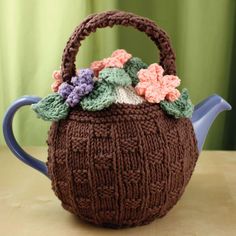 a knitted tea pot cover with flowers on it