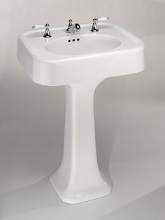 a white pedestal sink with three faucets on it