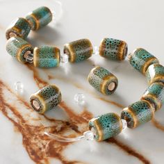 a close up of a necklace on a marble surface with beads attached to the clasp