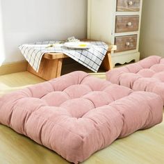 a pink futon mattress sitting on top of a wooden floor next to a dresser