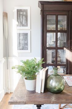 a wooden table topped with a potted plant next to an open book on top of it