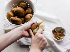 a person is peeling an apple in half on a white cloth next to a bowl of apples