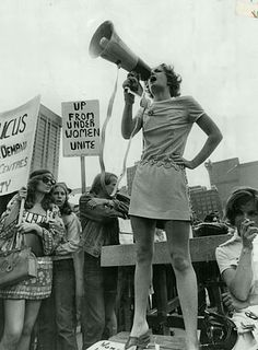 a woman speaking into a megaphone while standing in front of a group of people