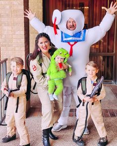 two adults and three children standing in front of a giant character