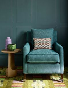 a chair and table in front of a green wall