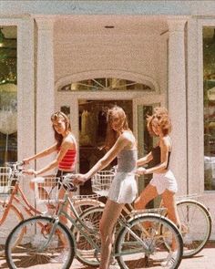 three girls are riding bikes in front of a store