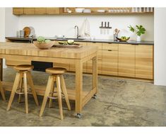 a kitchen with wooden cabinets and stools next to a counter top island in the middle