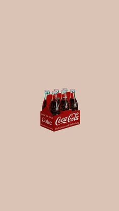 four bottles of coca - cola sitting on top of a cardboard box