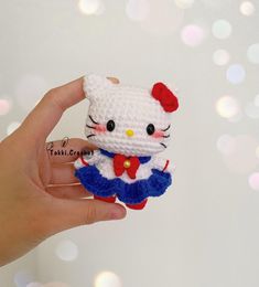 a hand holding a small crocheted hello kitty doll