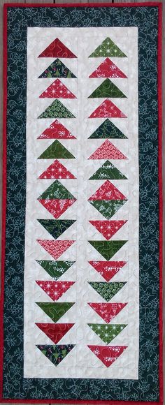 a quilted wall hanging with red, green and white christmas trees on the side