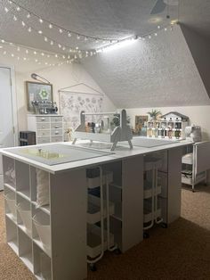 a white kitchen island with lots of drawers and lights on the ceiling above it in an attic space