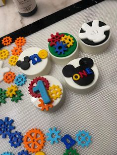 mickey mouse cupcakes are on the table with numbers and gears in front of them