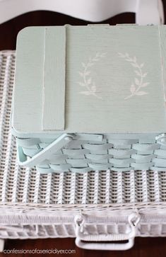 a wicker basket sitting on top of a table with a white painted box in the middle