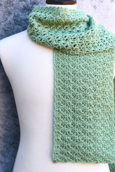 a green crocheted scarf on top of a mannequin