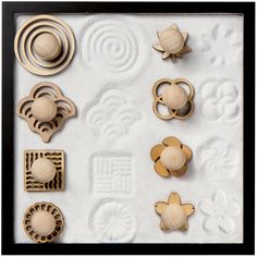 an assortment of carved wooden objects displayed in a black shadow box with white paper underneath