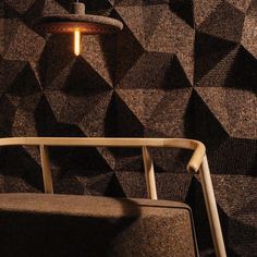 a brown chair sitting in front of a wall covered in black and white geometric tiles