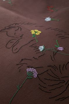 an embroidered fabric with flowers and leaves on the side, in various shades of brown