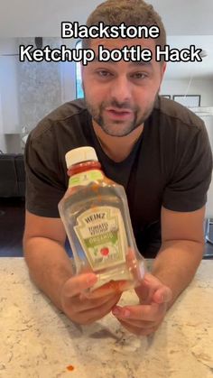 a man sitting at a table with a bottle of ketchup