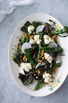 a white plate topped with broccoli and chickpeas covered in feta cheese